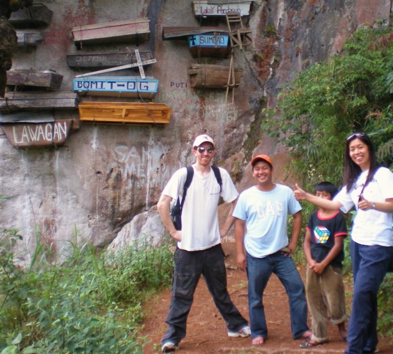 Brother James posing next to hanging coffins in Sagada with 3 Filipinos