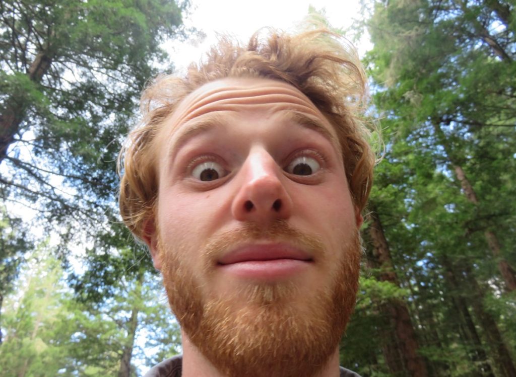 Giles Short selfie closeup of raised eyebrowed facial expression with trees behind