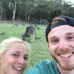 Giles Short selfie with girl smiling and kangaroos on grass behind