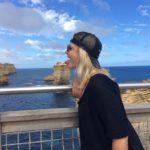 Girl with tongue out in front of rock formation by coast