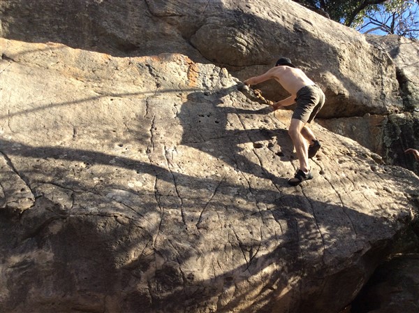 Giles Short rock climbing wearing shorts, hat and grippy shoes