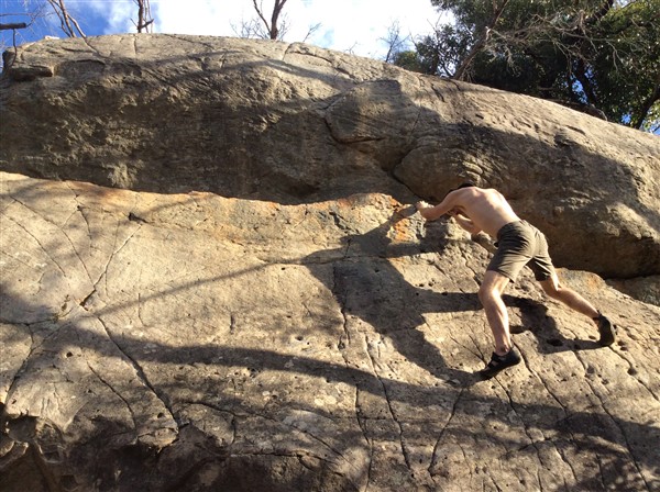 Giles Short rock climbing wearing shorts, hat and grippy shoes