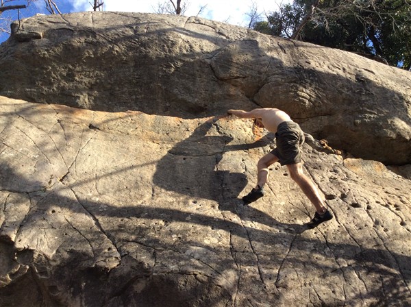 Giles Short rock climbing wearing shorts, hat and grippy shoes