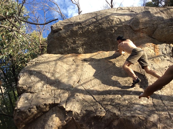 Giles Short rock climbing wearing shorts, hat and grippy shoes