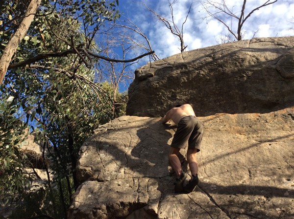 Giles Short rock climbing wearing shorts, hat and grippy shoes