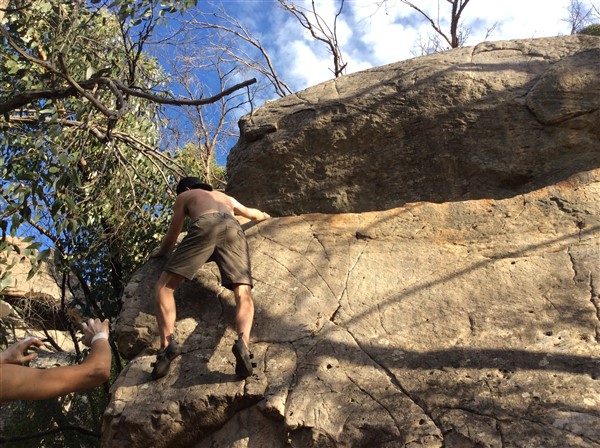 Giles Short rock climbing wearing shorts, hat and grippy shoes