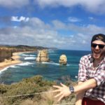 Giles Short posing with coastline and sea behind